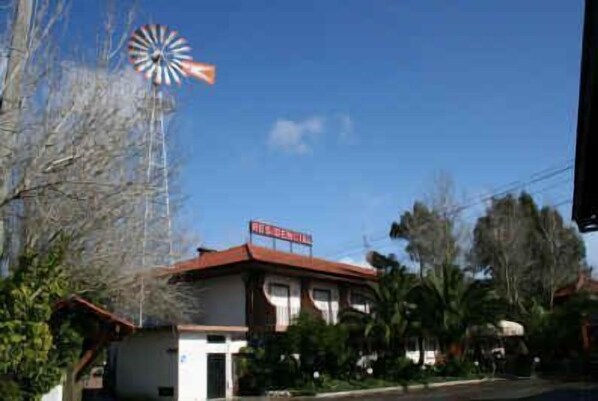 Un edificio con techo rojo y un molino de viento al fondo.