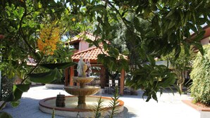 A courtyard with a fountain, surrounded by lush greenery and a building with a tiled roof. - Hotel João Capela (Aveiro)