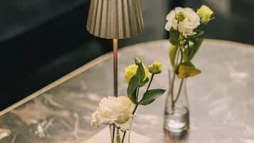 Ein Marmortisch mit zwei Glasvasen, in denen Blumen stehen, und einer Lampe.