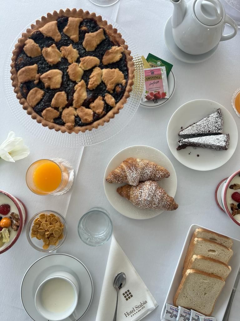 A breakfast setting with a pie, pastries, and various breakfast items on a table.