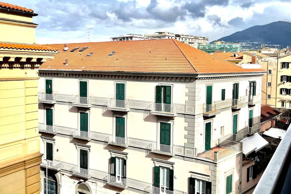 A multi-story building with balconies and green shutters.