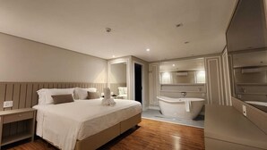 A modern hotel room with a large bed, a separate bathroom with a bathtub, and a walk-in closet. - Del Rey Quality Hotel (Foz do Iguaçu)