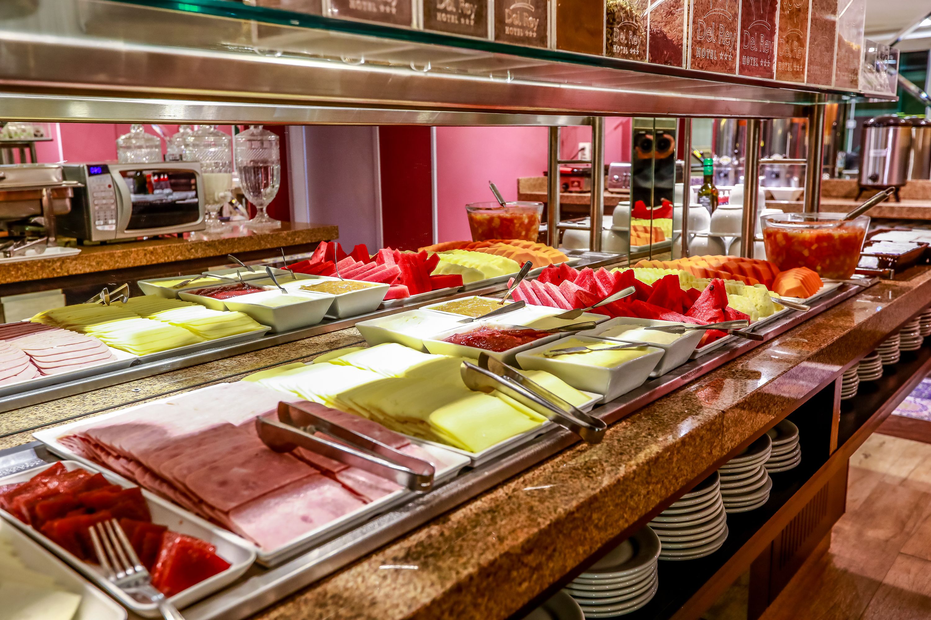 A buffet with various food items including meats, cheeses, and fruits.