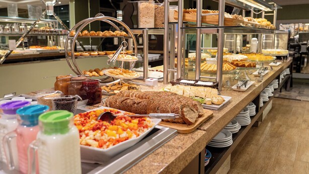 A buffet with various food items, including pastries, bread, and a large loaf of bread. - Del Rey Quality Hotel (Foz do Iguaçu)