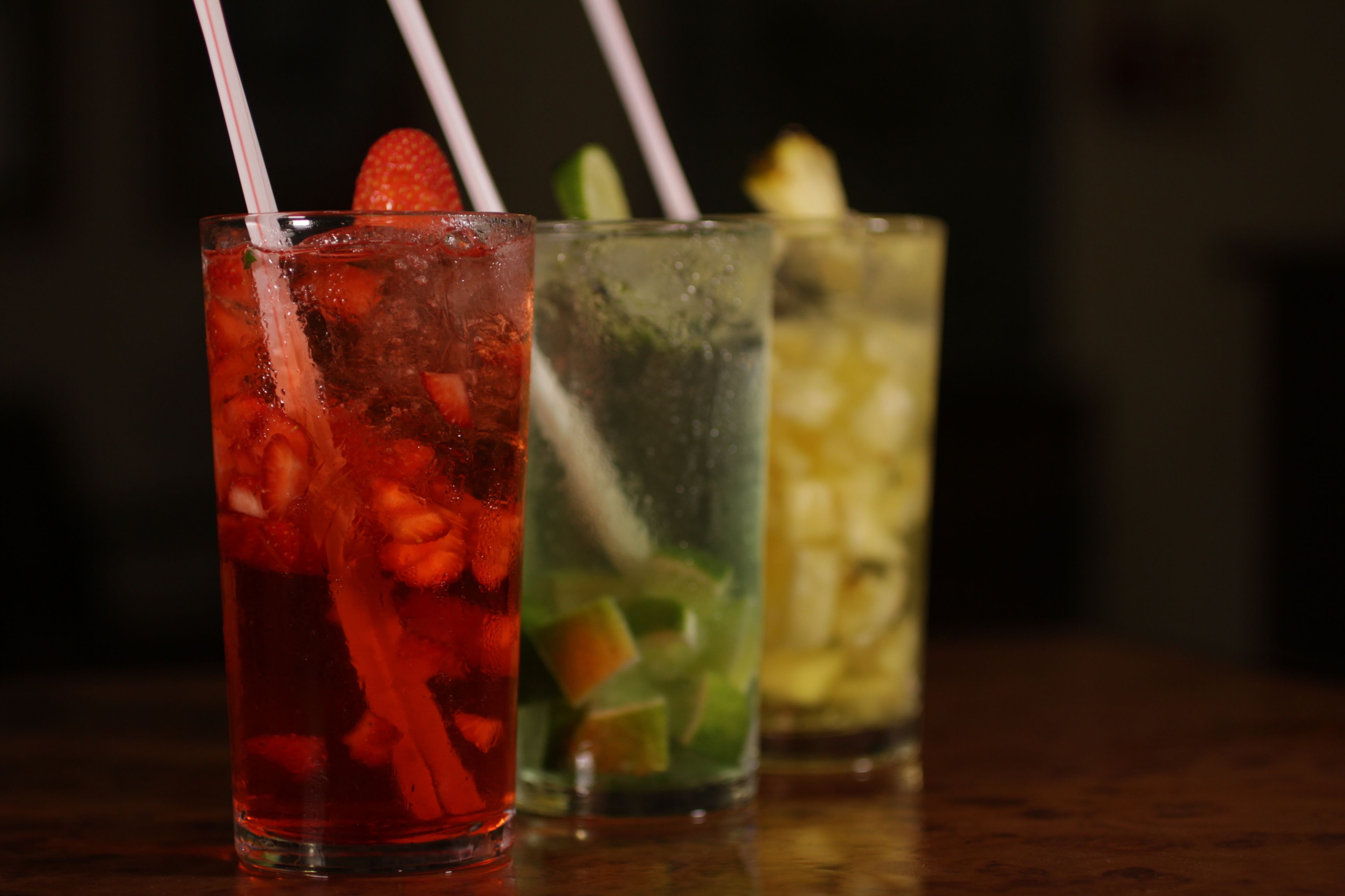 Tres gots de begudes fredes amb gots i talls de fruita.