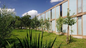 A modern building with large glass windows and a well-maintained grassy area with trees. - Hörger Biohotel und Tafernwirtschaft (Kranzberg)