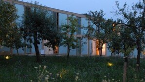 A modern building with large windows and a garden area with trees and plants. - Hörger Biohotel und Tafernwirtschaft (Kranzberg)