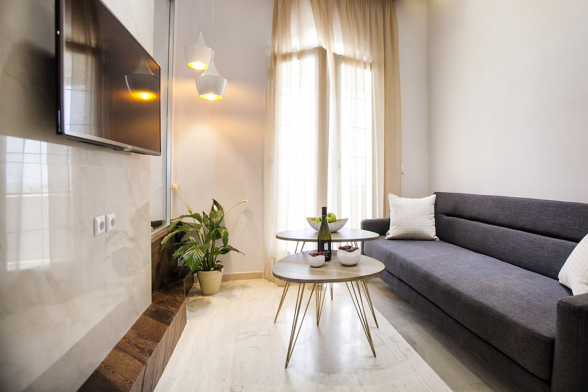 Un salon moderne avec un canapé gris, une table basse ronde et une plante en pot.