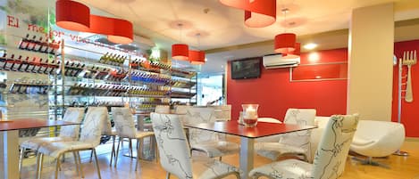 En restaurang med en inredning som inkluderar en vinhylla, röda väggar och moderna möbler.