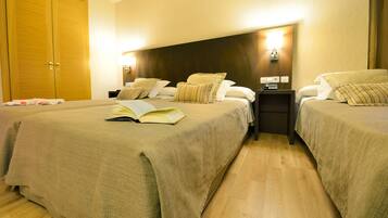 Een hotelkamer met twee bedden, een houten garderobe en een nachtkastje met een lamp.