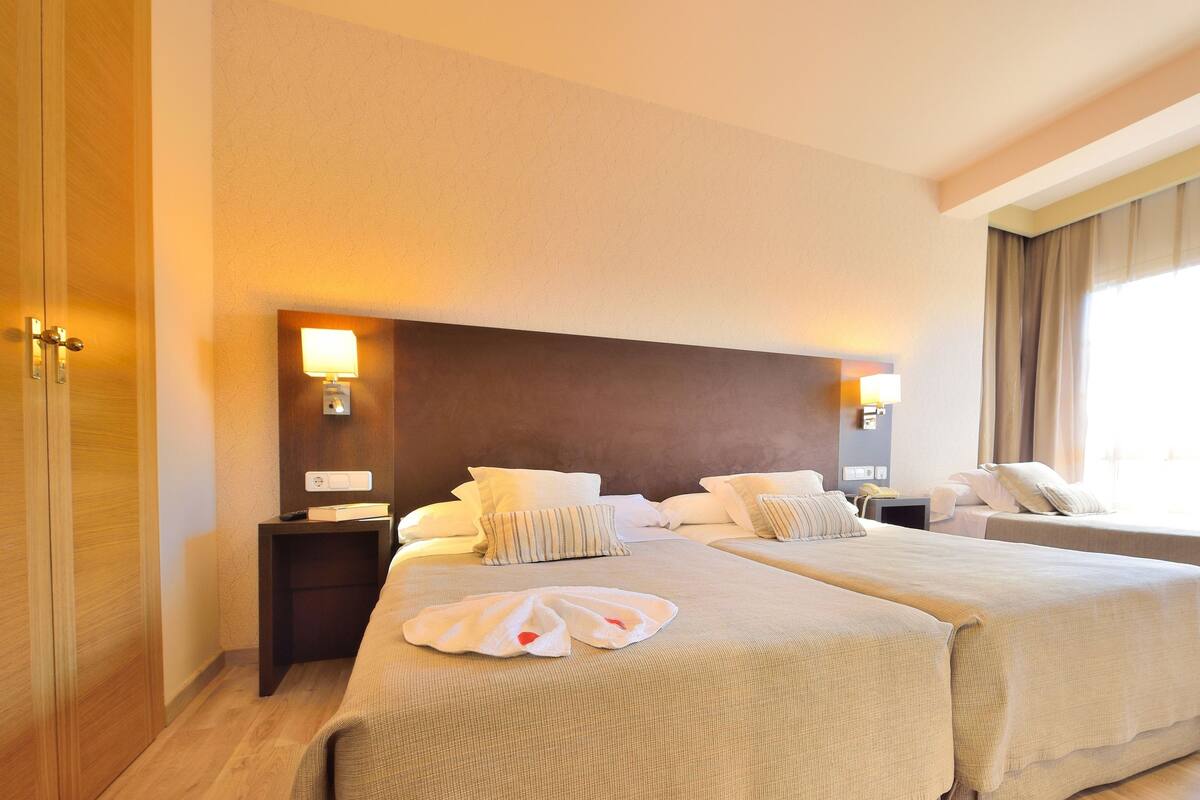 Une chambre d’hôtel avec deux lits, un bureau et une chaise.