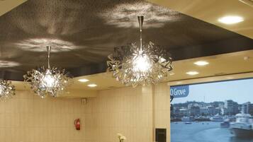 Un interior moderno con tres candelabros, un extintor y un amplio ventanal que muestra un paisaje urbano.