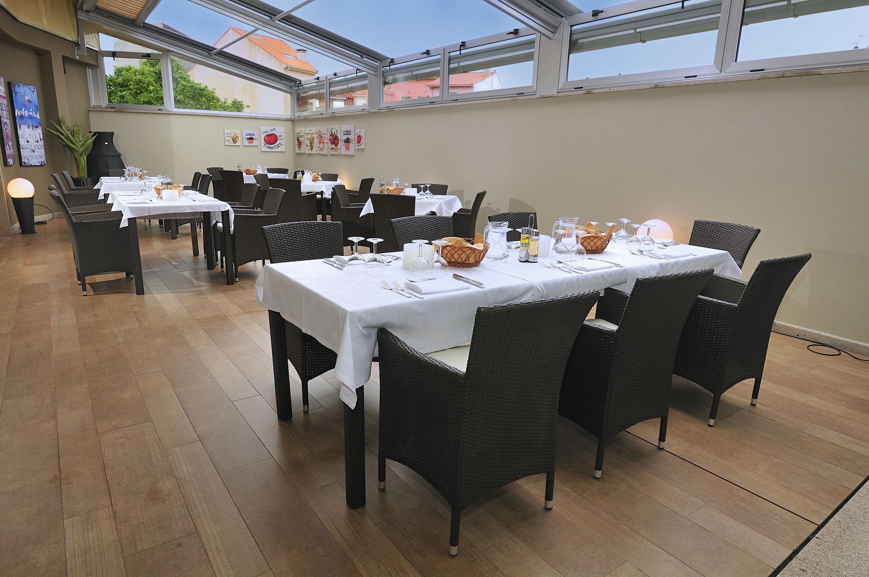 A restaurant with multiple tables set for dining, featuring wicker chairs and white tablecloths.