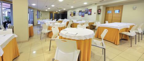 A conference room with multiple tables and chairs, arranged in rows.