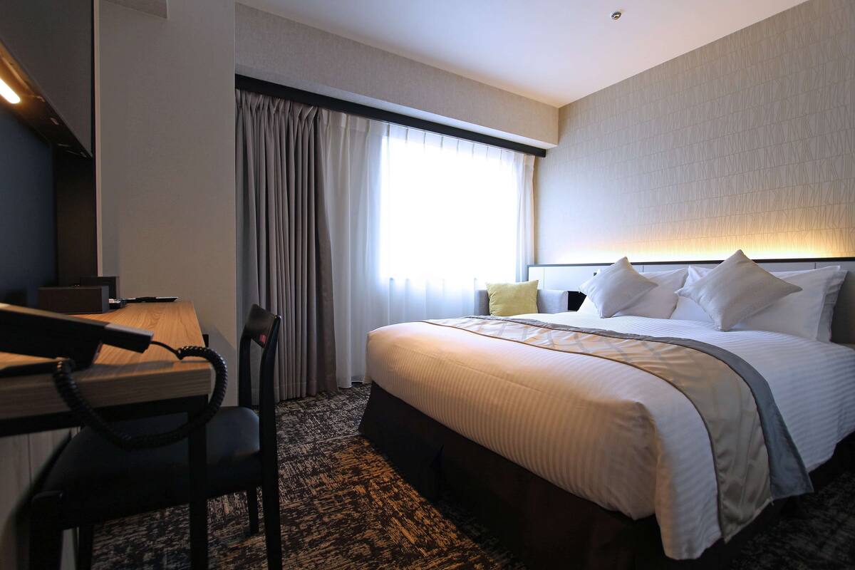 Una habitación de hotel con cama, escritorio y silla.