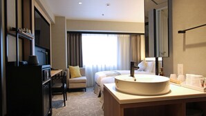 Una habitación de hotel con una cama grande, un escritorio, un televisor y un baño con lavamanos y espejo.