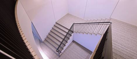 A modern interior with a spiral staircase, white walls, and a tiled floor.