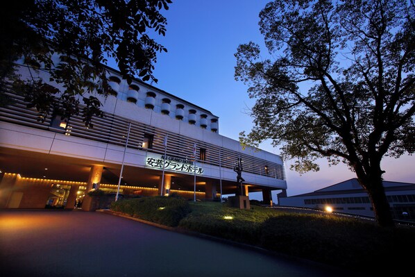 A modern hotel with a covered entrance, large windows, and a sign in a foreign language. - Aki Grand Hotel & Spa (Hatsukaichi)