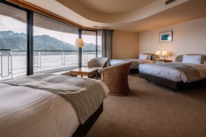 Ein Hotelzimmer mit zwei Betten, einem Sessel, einem Tisch und einem großen Fenster mit Bergblick.