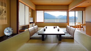 A traditional Japanese room with tatami flooring, a low table, and cushions. - Aki Grand Hotel & Spa (Hatsukaichi)