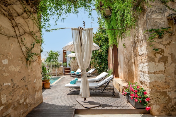 Una piscina al aire libre, sombrillas, sillones reclinables de piscina