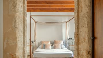 Une chambre à coucher avec un lit à baldaquin, des murs en pierre et un plafond en bois.