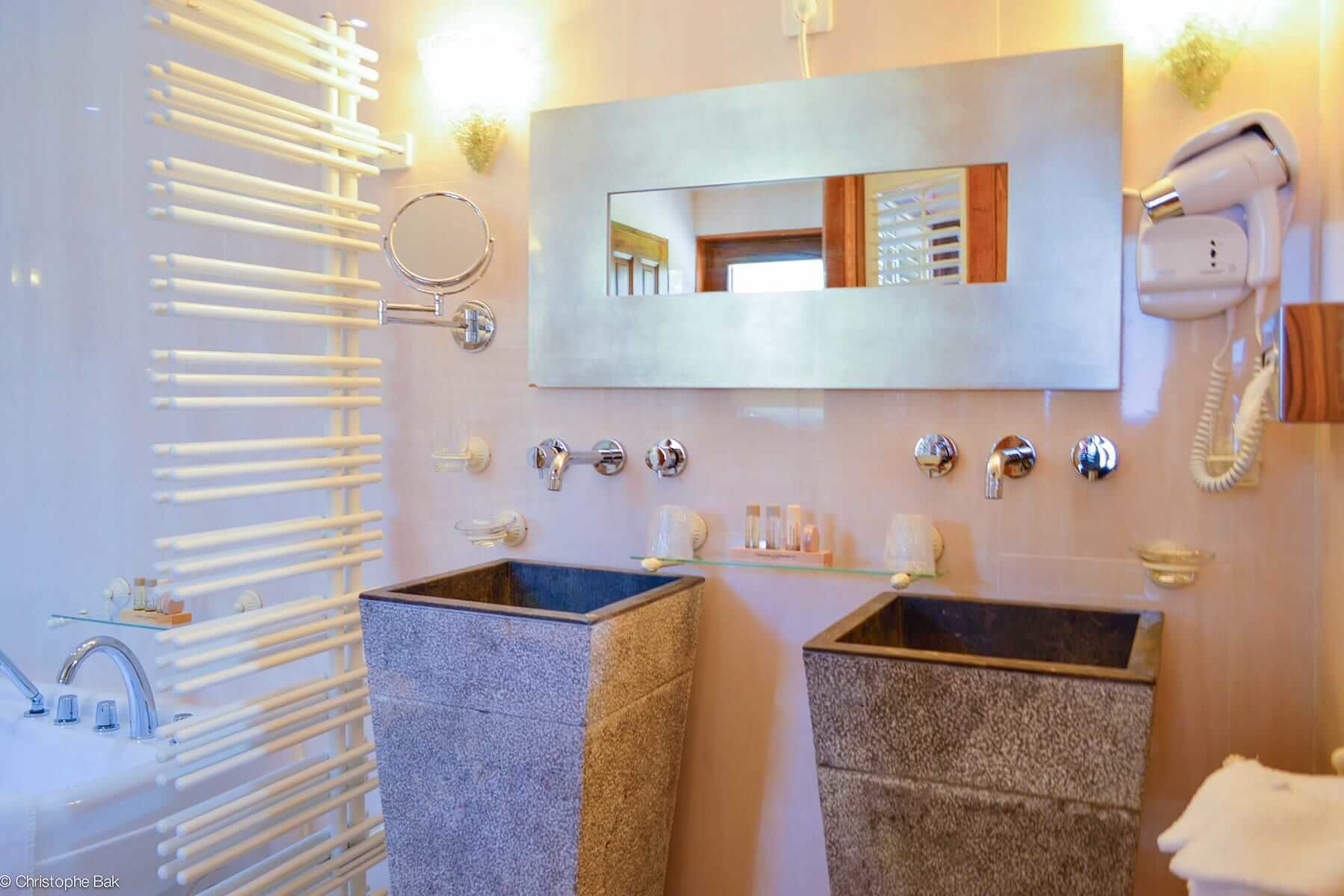 Un baño moderno con bañera, dos lavamanos, un espejo, secador de pelo y toallero.