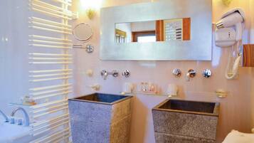 Un baño moderno con bañera, dos lavamanos, un espejo, secador de pelo y toallero.