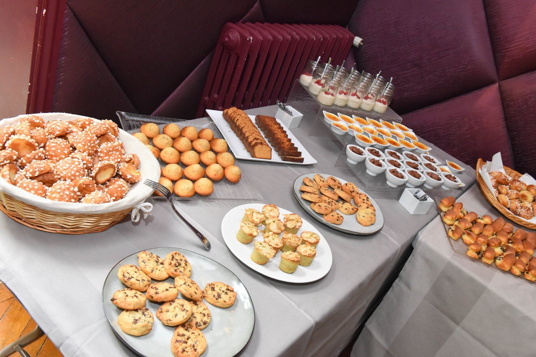 A buffet table with various baked goods, including cookies, pastries, and bread.