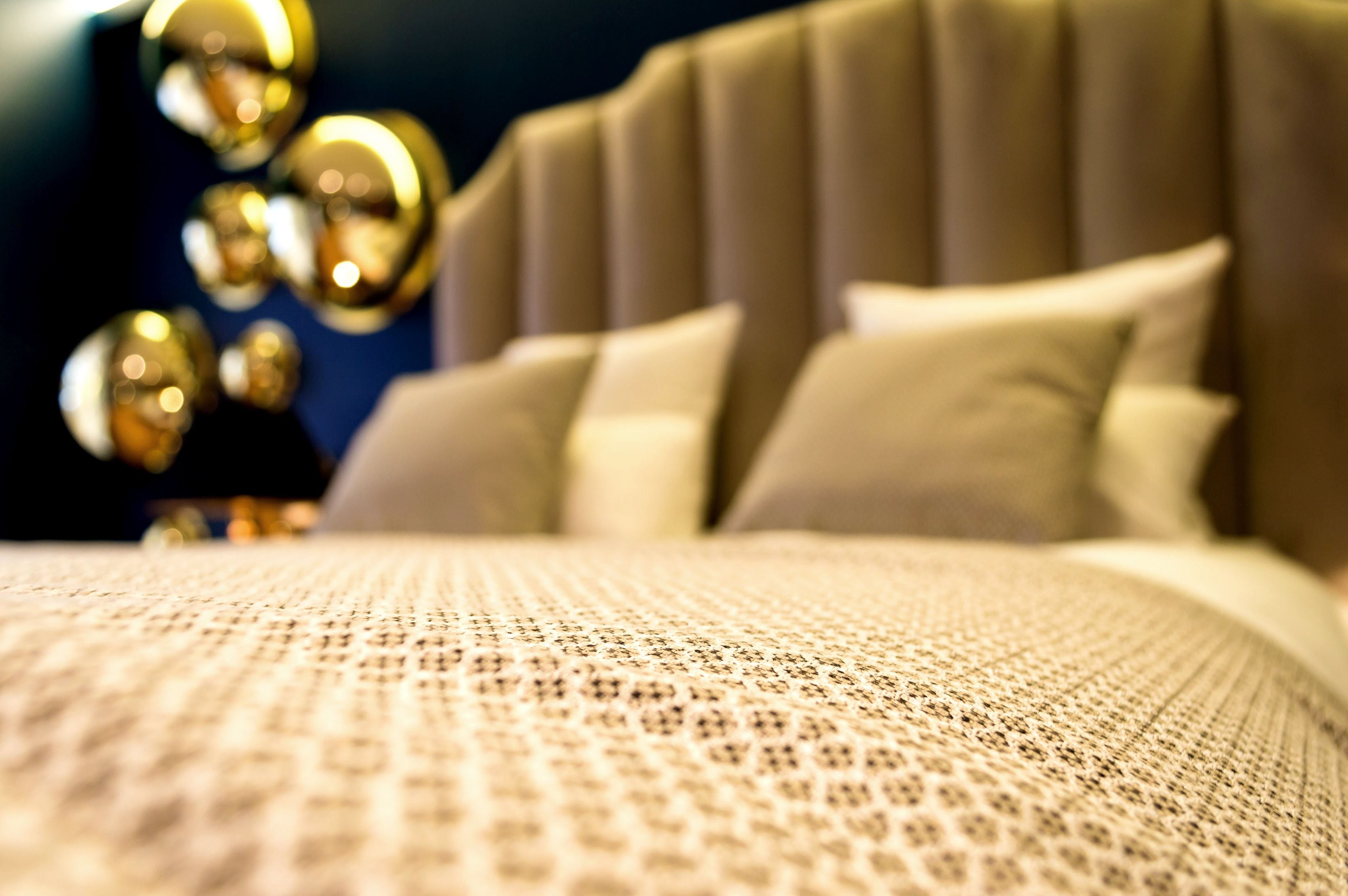 A close-up of a textured bedspread with a ribbed headboard and pillows.