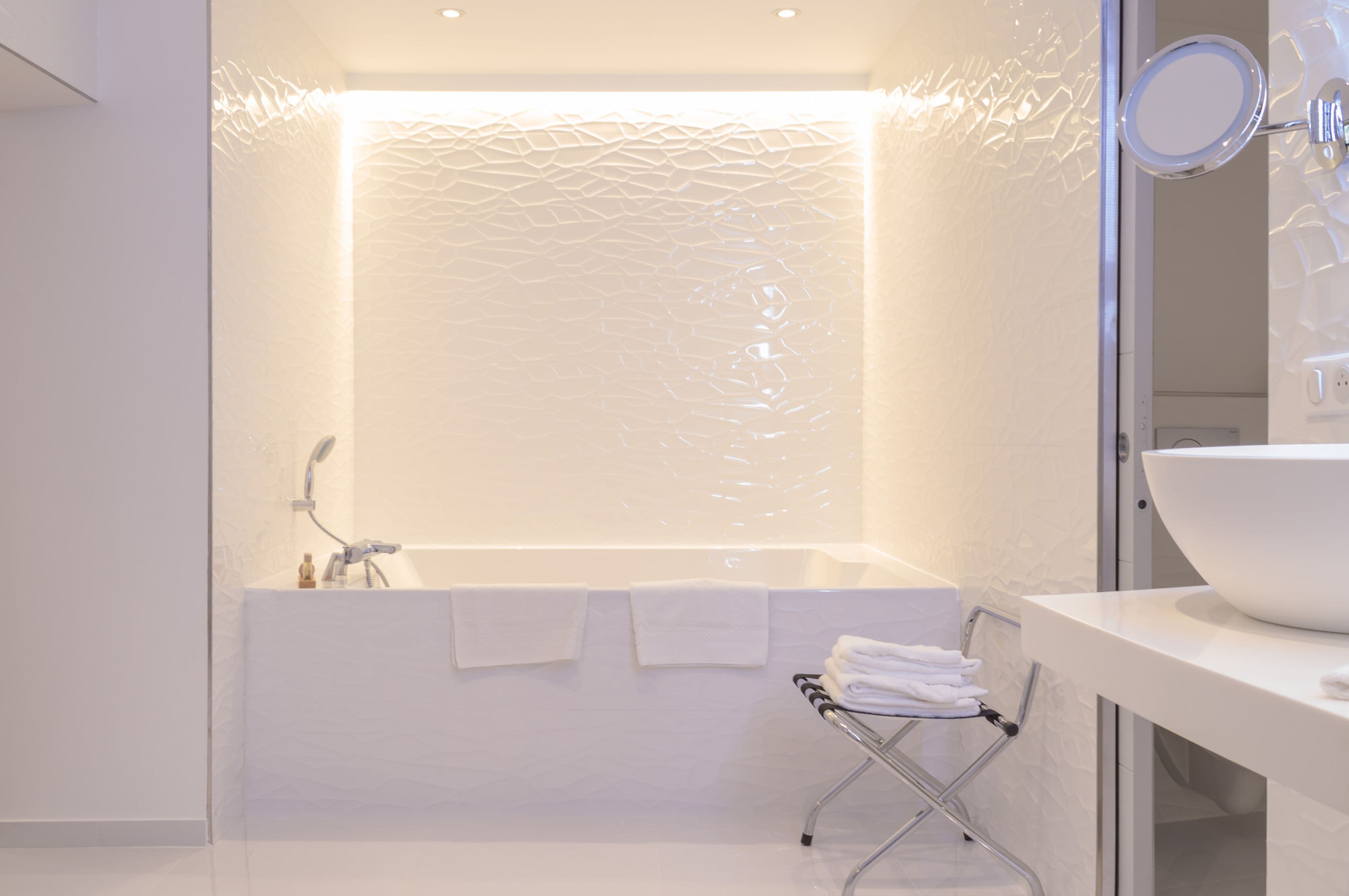 A modern bathroom with a large bathtub, a white sink, and a glass shower enclosure.