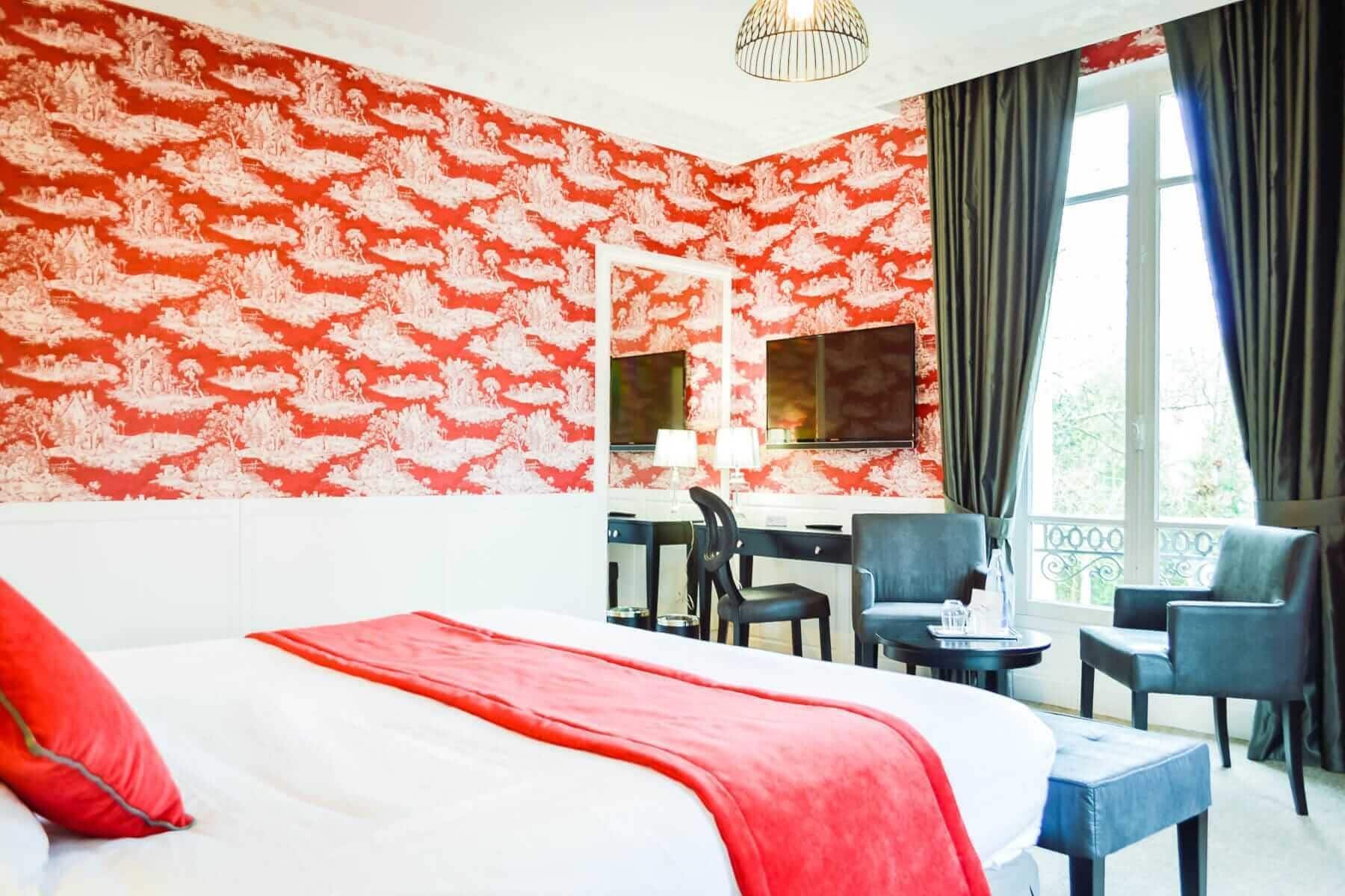 Een hotelkamer met een groot bed, een bureau met twee stoelen, een televisie en een raam met gordijnen.