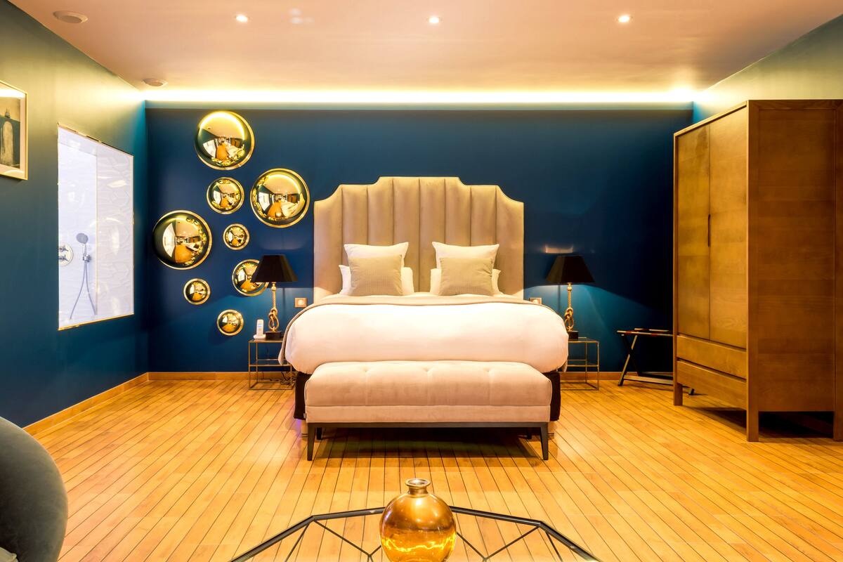 A bedroom with a large bed, a wardrobe, and multiple mirrors on the wall.