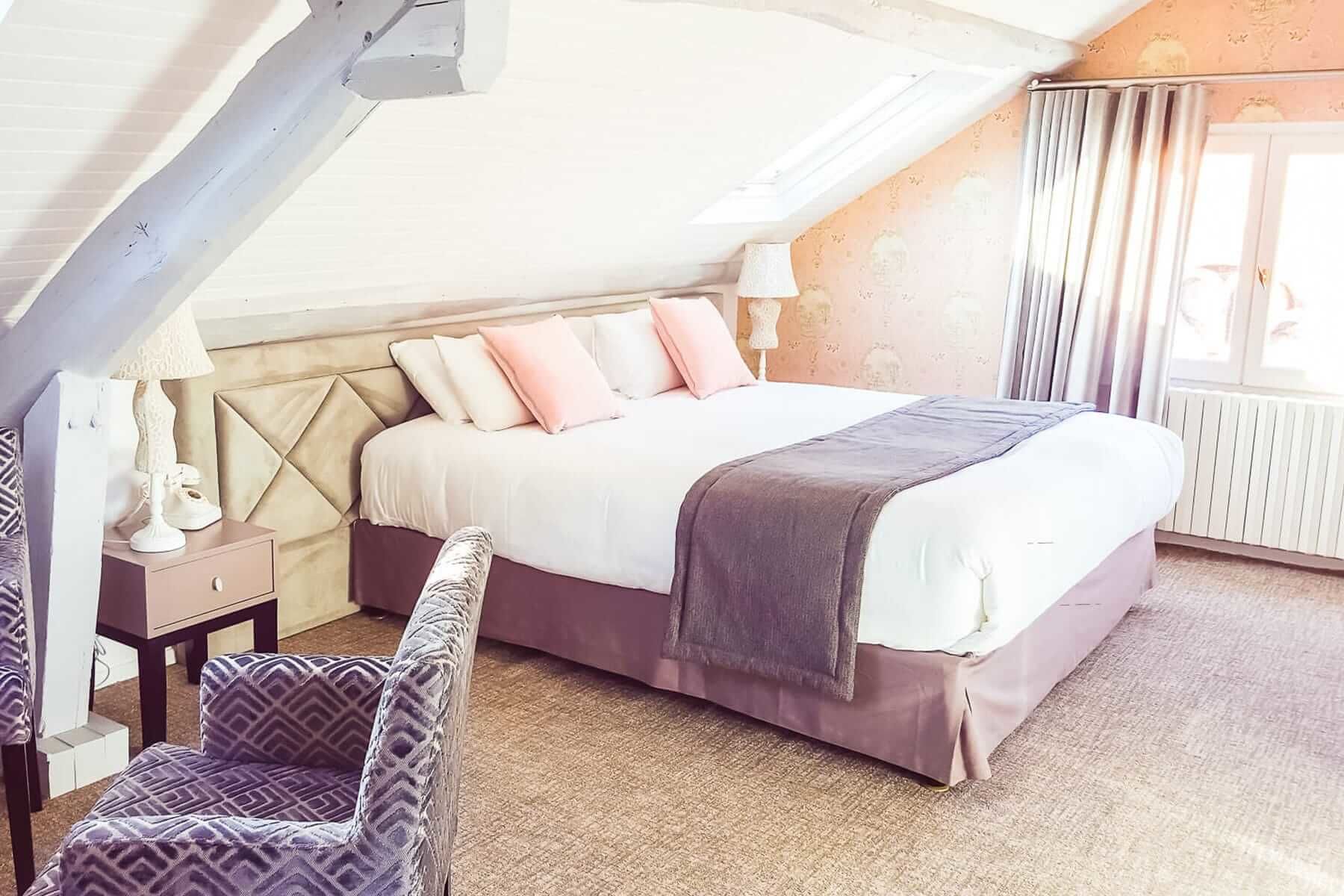 Un dormitorio con cama, una silla, una mesita de noche y una lámpara.