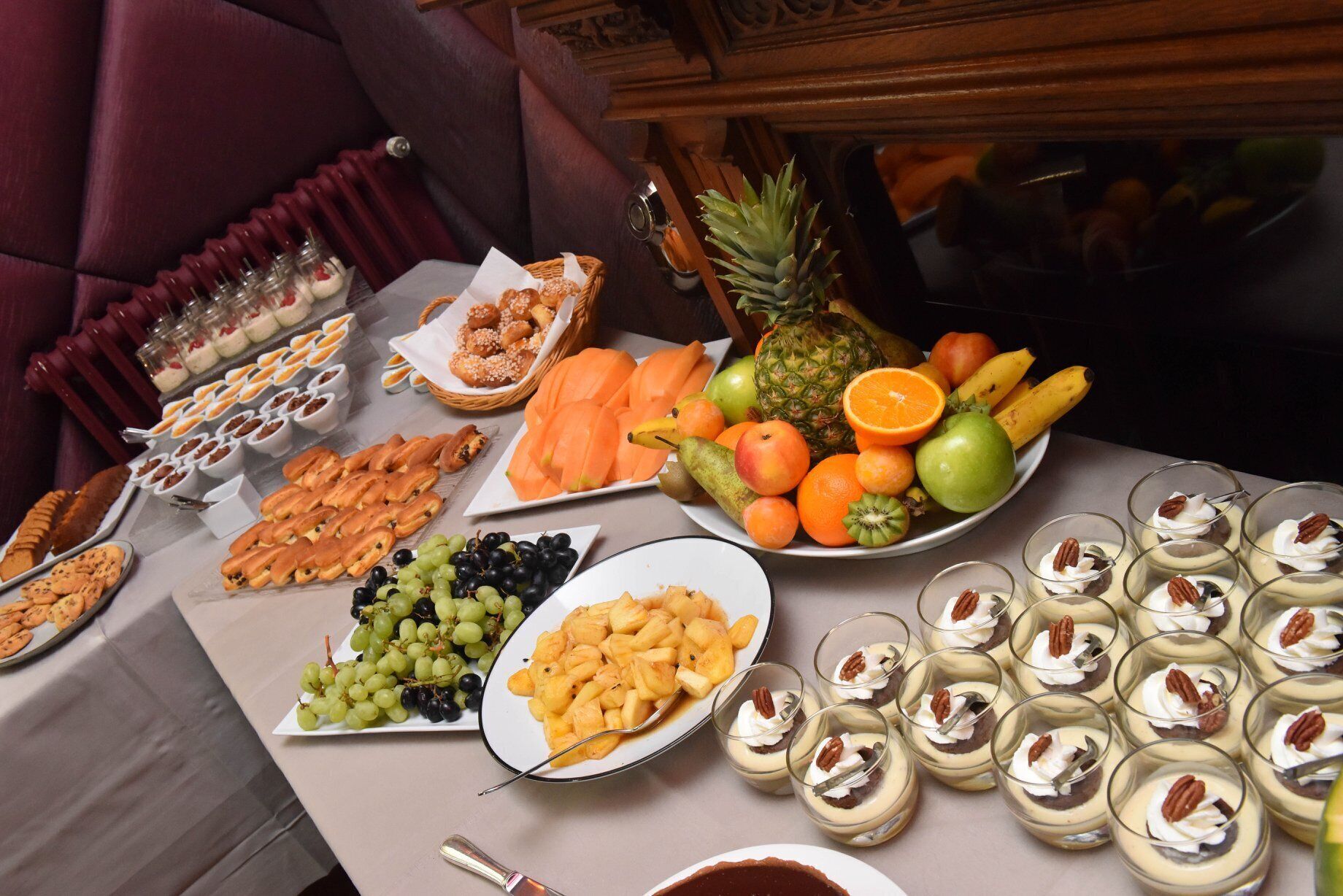 A buffet table with various food items including fruits, pastries, and desserts.