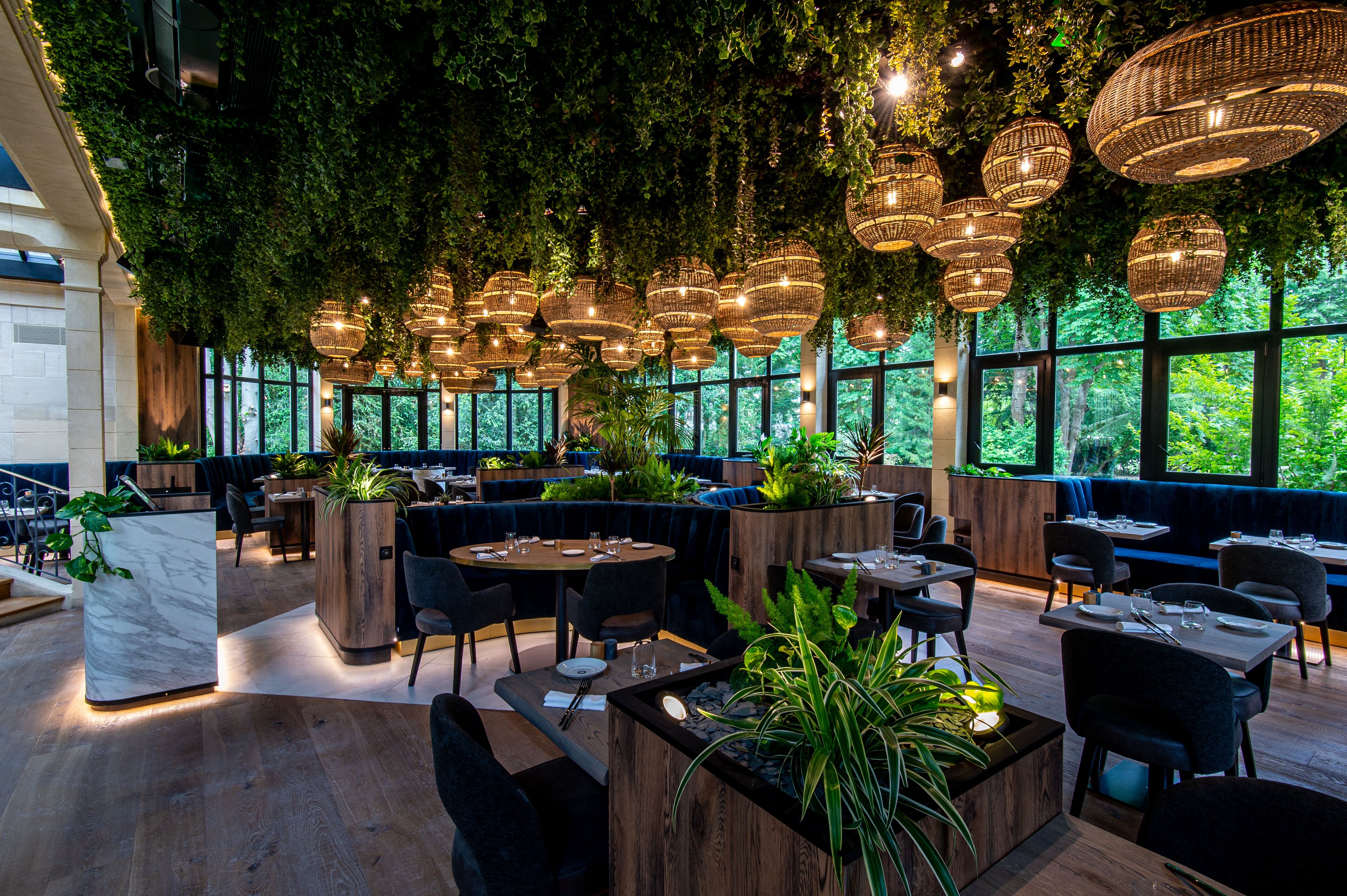 A restaurant with round tables, dark chairs, and hanging wicker lamps.