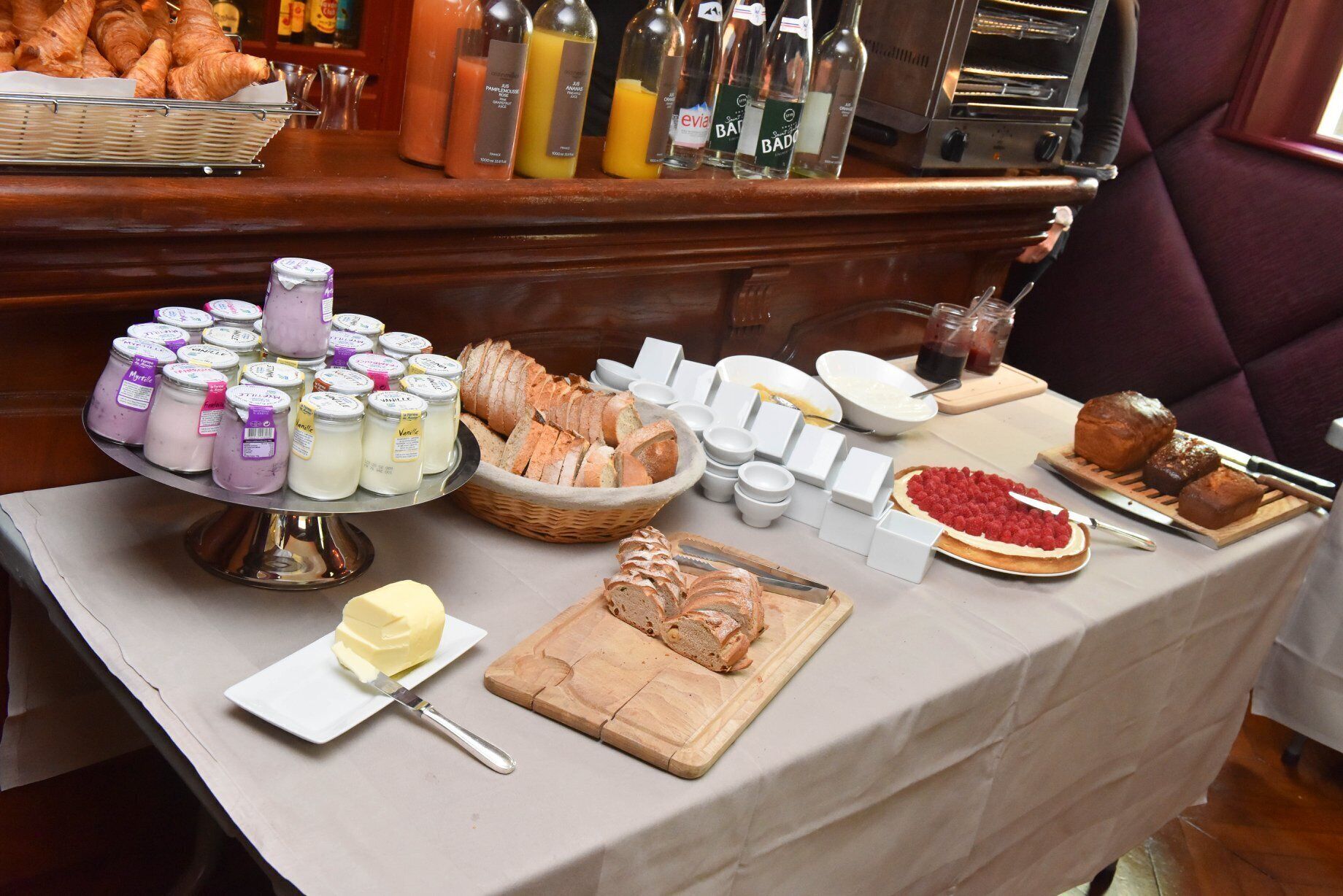 A breakfast buffet with pastries, bread, jams, and spreads.
