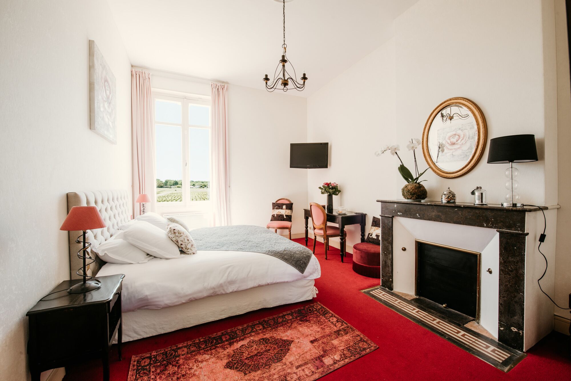 Un dormitorio con cama, chimenea, televisor y ventana con cortinas.