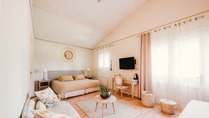 Un dormitorio con cama, mesitas de noche, escritorio, silla, televisor y ventana con cortinas.