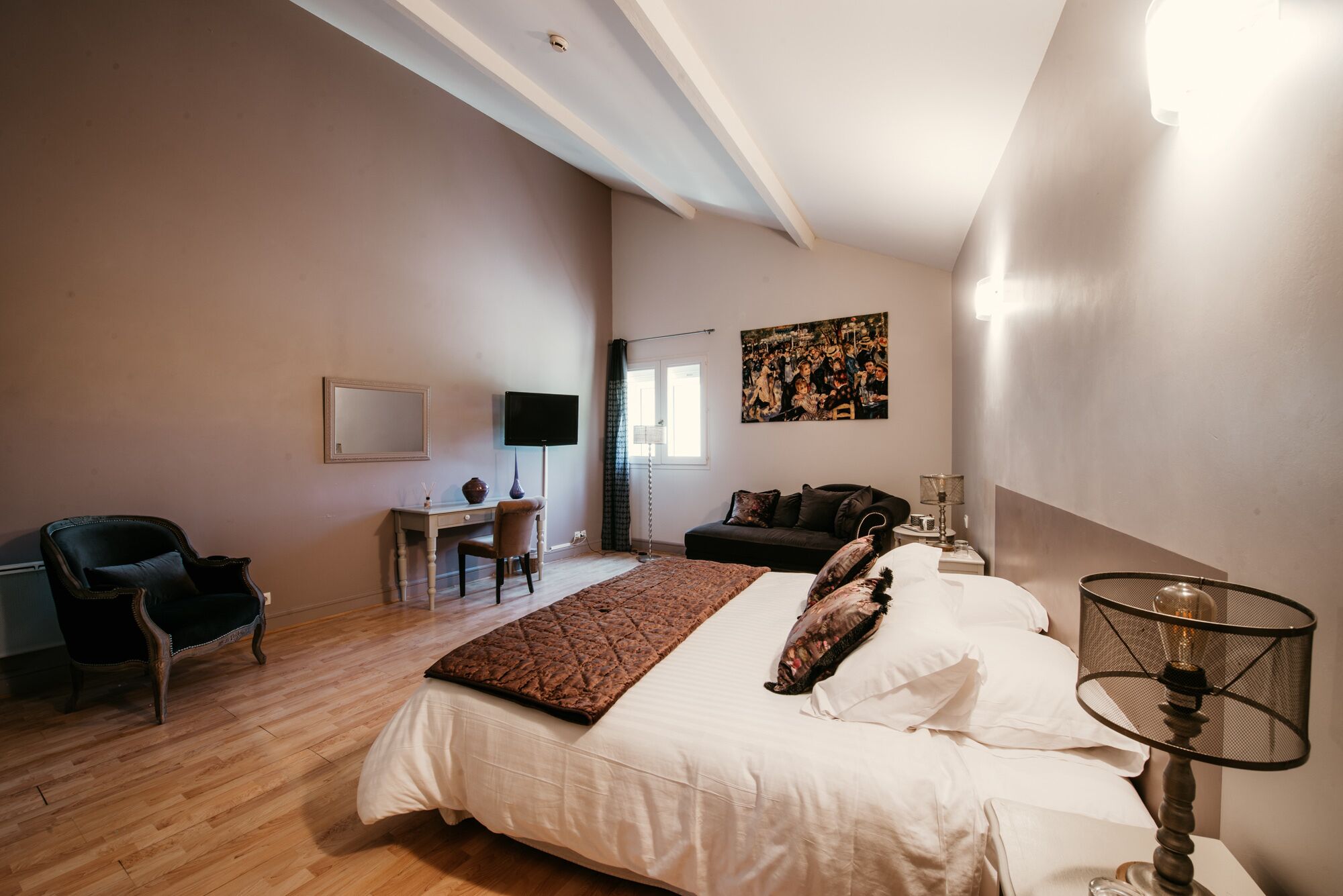 Une chambre à coucher avec un grand lit, un bureau, une chaise, une télévision et un tableau au mur.