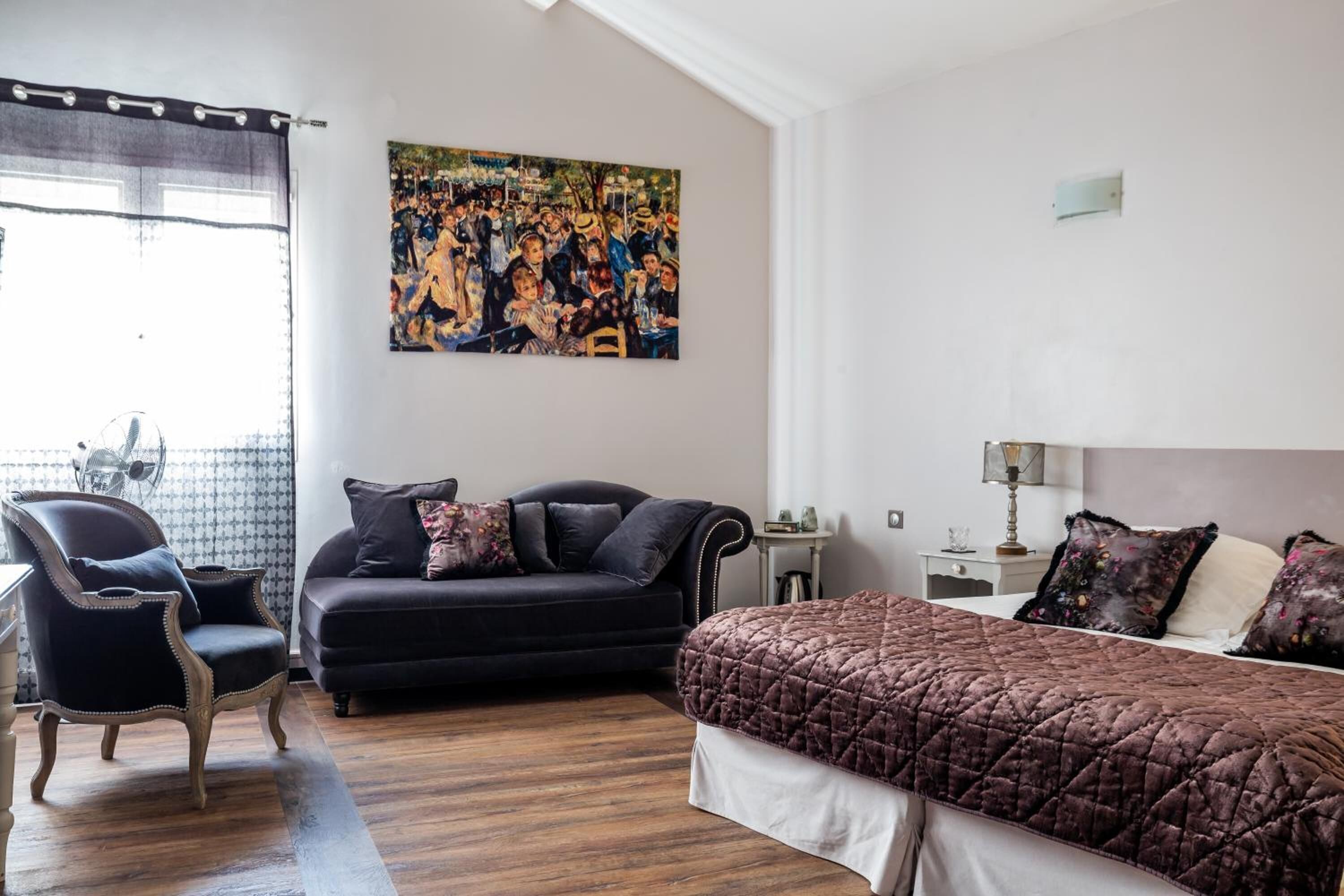 Ein Zimmer mit einem Bett, einem Schlafsofa, einem Sessel und einem Bild an der Wand.