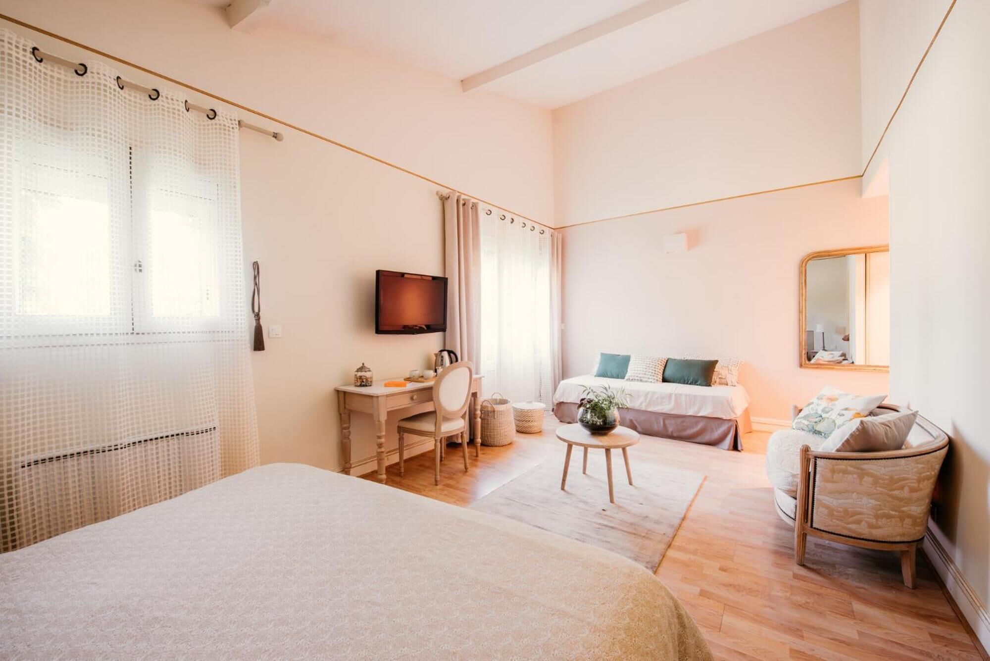 Un dormitorio con cama, escritorio, silla, televisor y espejo.