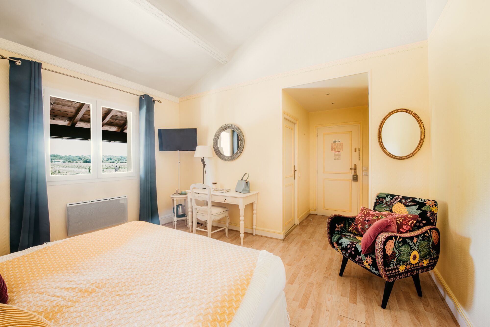 A hotel room with a bed, a desk, a chair, and a window with curtains.