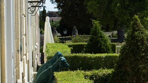 Un edificio con un jardín bien cuidado, con setos y una estatua.