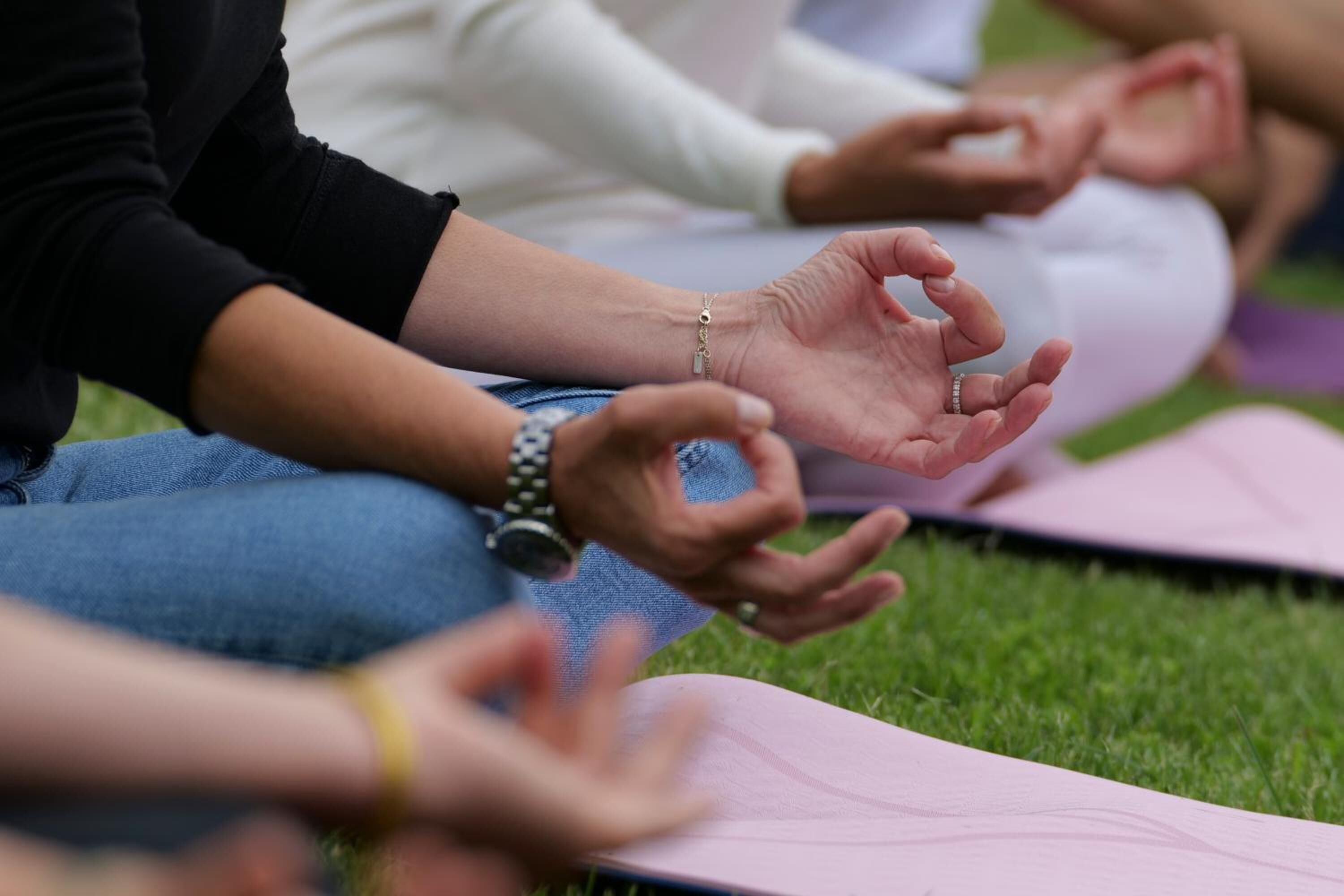 People sitting on yoga mats outdoors.