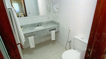 Un baño pequeño y limpio con lavamanos, espejo y retrete blancos.