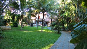 A stone pathway leading to a building surrounded by lush greenery and palm trees. - Pousada Dos Reis (Búzios)