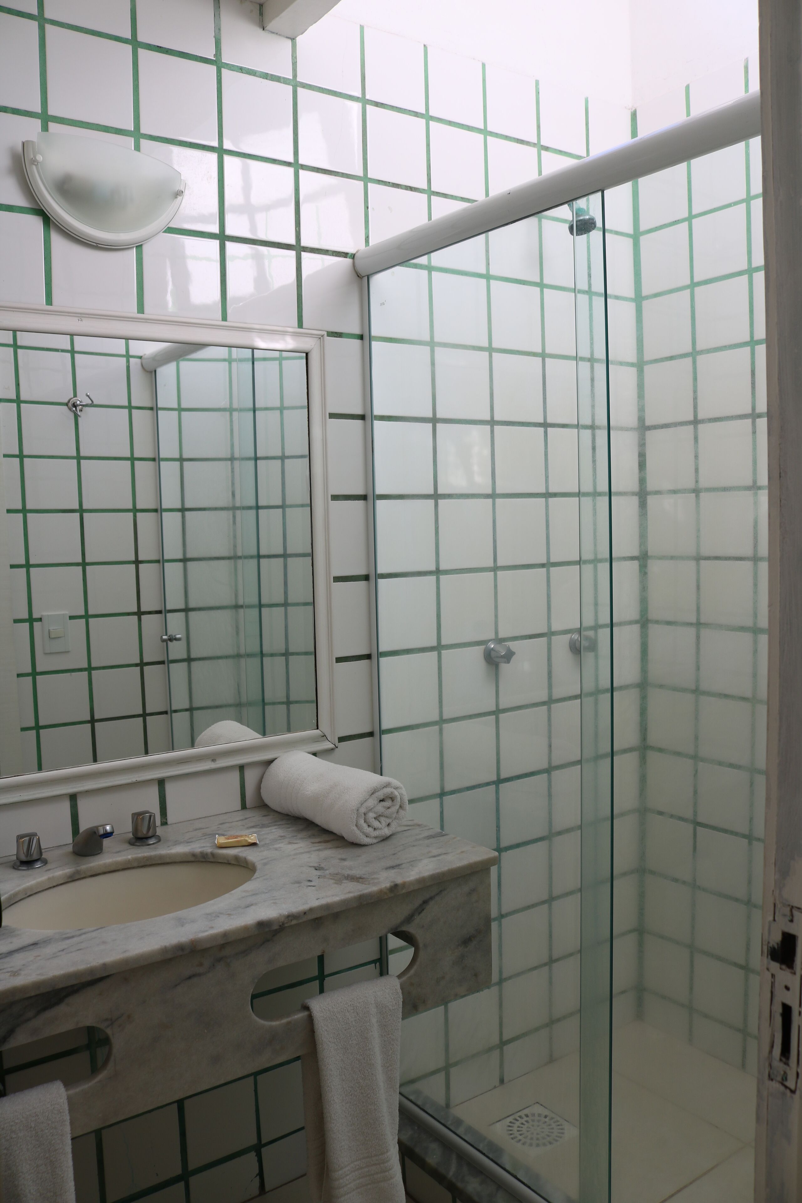 A bathroom with a marble sink, a mirror, and a glass shower enclosure.