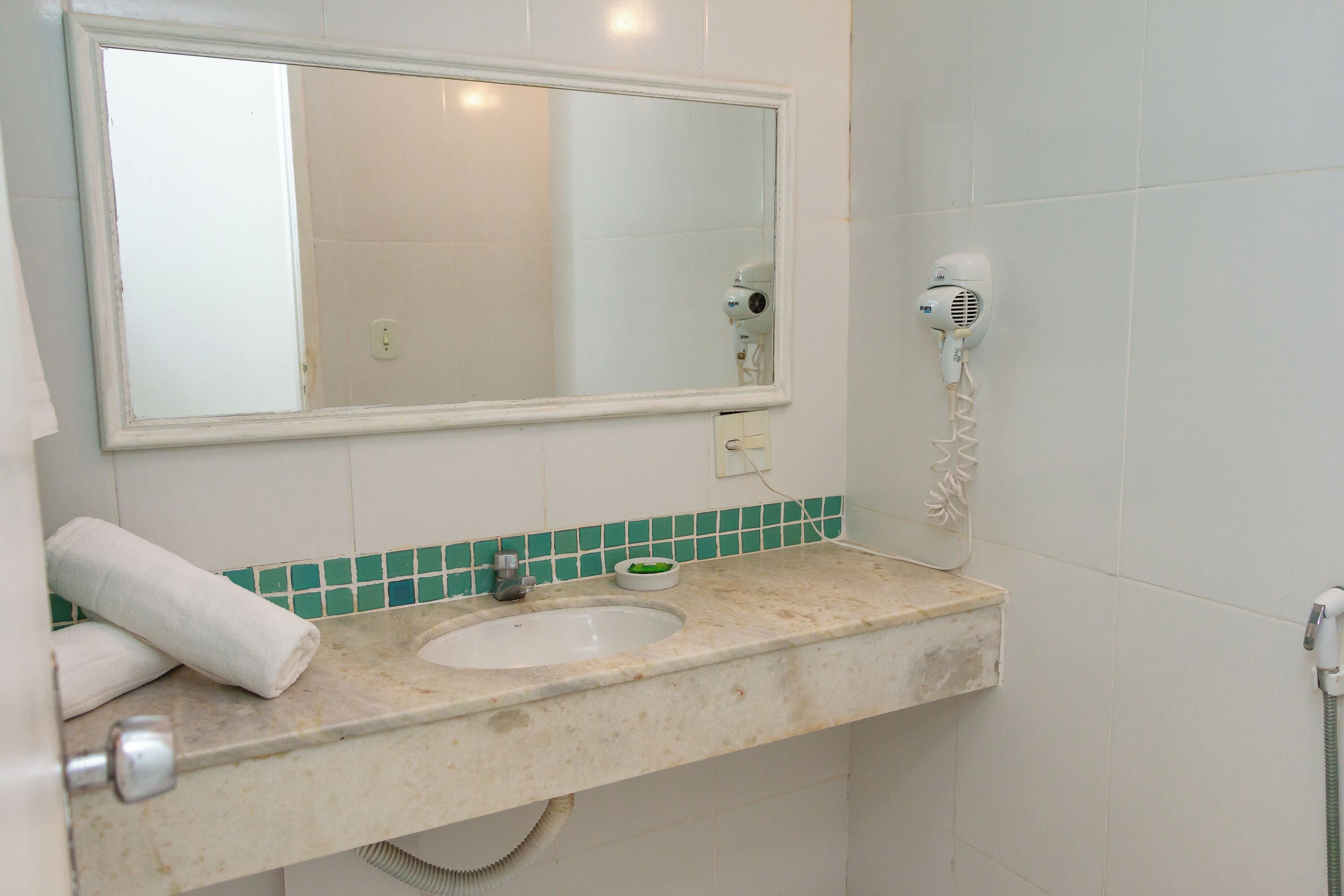 A bathroom with a sink, mirror, towel, and hairdryer.
