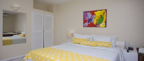 A hotel room with a bed, a bedside table with a lamp, a phone, and a painting on the wall.